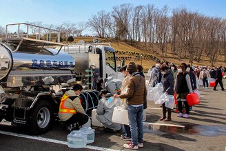 Residents queue to fill containers with water from a tanker truck in Minamisoma, Fukushima prefecture on March 17, 2022, after the water was cut off following a 7.3-magnitude quake that jolted east Japan the night before.