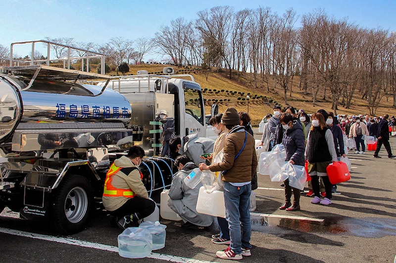 Residents queue to fill containers with water from a tanker truck in Minamisoma, Fukushima prefecture on March 17, 2022, after the water was cut off following a 7.3-magnitude quake that jolted east Japan the night before.