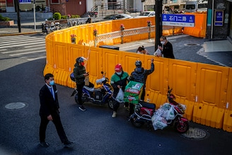 A delivery worker passes food to a man over the barriers of an area under lockdown amid the Covid-19 pandemic, in Shanghai, China on March 23, 2022.