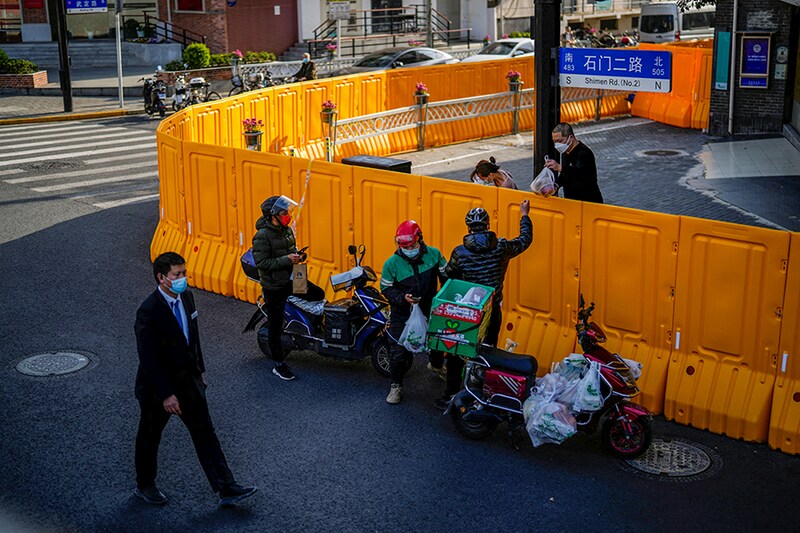 A delivery worker passes food to a man over the barriers of an area under lockdown amid the Covid-19 pandemic, in Shanghai, China on March 23, 2022.