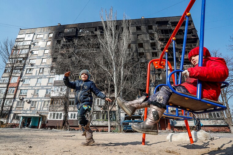 Children play in front of a building, damaged in fighting during Ukraine-Russia conflict, in the besieged southern port of Mariupol, Ukraine on March 23, 2022.
