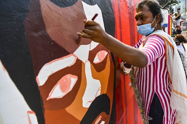 A member of the transgender community and of the of Aravani Art Project, a women and trans-women art collective, paints a mural in a wall along a street in Mumbai. Image: Indranil Mukherjee / AFP