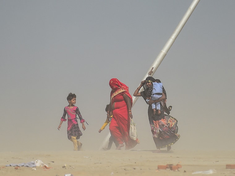 A family weathers a dust storm on their walk home at Sangam, the confluence of the Ganga and Yamuna rivers in Prayagraj, on March 29, 2022.