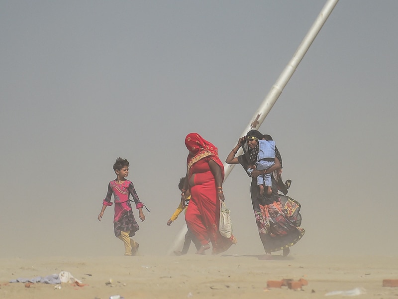 A family weathers a dust storm on their walk home at Sangam, the confluence of the Ganga and Yamuna rivers in Prayagraj, on March 29, 2022.