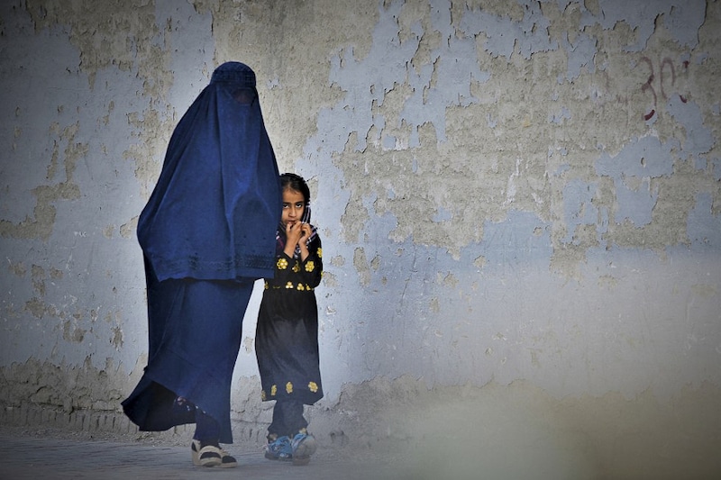 A burqa-clad woman walks with her child along a street in Kabul, Afghanistan on May 7, 2022. The Taliban announced harsher restrictions yesterday on women since they seized power, ordering them to cover themselves fully in public. Today the world celebrates Mothers" Day.