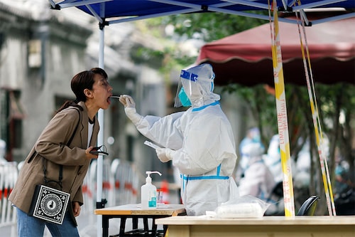 A worker in a protective suit collects a swab from a resident at a makeshift nucleic acid testing site amid the coronavirus disease (COVID-19) outbreak, in Beijing, China May 9, 2022. ​(Credits: Carlos Garcia Rawlins/ Reuters) A worker in a protective suit collects a swab from a resident at a makeshift nucleic acid testing site amid the coronavirus disease (COVID-19) outbreak, in Beijing, China May 9, 2022. ​(Credits: Carlos Garcia Rawlins/ Reuters)