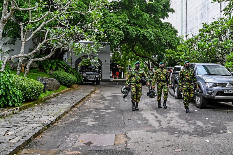 Members of Sri Lankan security personnel walk inside Sri Lanka"s outgoing prime minister Mahinda Rajapaksa"s official residence "Temple Trees", a day after it was breached by the protesters in Colombo on May 10, 2022. Sri Lanka deployed thousands of troops and police on May 10 to enforce a curfew after five people were killed in the worst violence in weeks of protests over an unprecedented economic crisis.