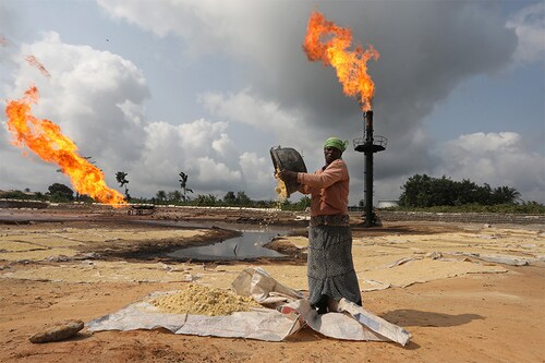 A woman near a gas flaring furnace in Ughelli, Delta State, Nigeria September 17, 2020. (Credits: Afolabi Sotunde/ Reuters)