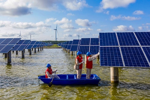 This photo taken on July 19, 2021 shows electrical workers in a boat as they check solar panels at a photovoltaic power station built in a fishpond in Haian in China"s eastern Jiangsu province. (Credits: AFP / China OUT) This photo taken on July 19, 2021 shows electrical workers in a boat as they check solar panels at a photovoltaic power station built in a fishpond in Haian in China"s eastern Jiangsu province. (Credits: AFP / China OUT)