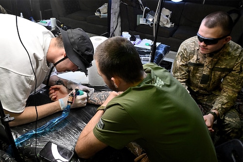 Ukrainian servicemen get tattoos during the “Art Weaponâ€ festival in Kyiv on May 14, 2022. Image: Sergei SUPINSKY / AFP
