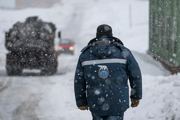 A man wearing an anorak with the logo of Arktikugol company on the back walks in the blizzard on May 7, 2022, in the miners" town of Barentsburg, on the Svalbard Archipelago, northern Norway.â€‹ (Credits: Jonathan NACKSTRAND / AFP)