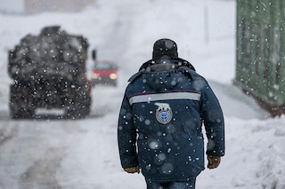 A man wearing an anorak with the logo of Arktikugol company on the back walks in the blizzard on May 7, 2022, in the miners" town of Barentsburg, on the Svalbard Archipelago, northern Norway.​ (Credits: Jonathan NACKSTRAND / AFP)