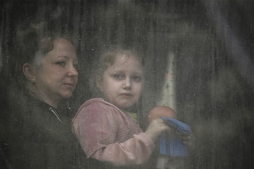A mother with her daughter sit inside a bus as they evacuate the city of Bakhmut in the eastern Ukranian region of Donbas on May 22, 2022, amid Russian invasion of Ukraine.â€‹ (Credits: ARIS MESSINIS / AFP)