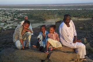 A family poses for a picture on a rock overlooking the Nile River and Karima city in Sudan"s Northern State, on October 29, 2022. Climate change, pollution and exploitation by man is putting existential unsustainable pressure on the world"s second longest river on which millions of Africans depend. Image: ASHRAF SHAZLY / AFP