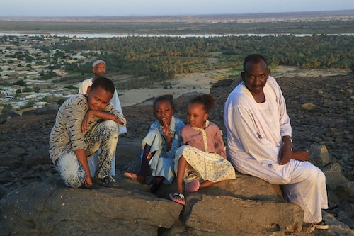 A family poses for a picture on a rock overlooking the Nile River and Karima city in Sudan"s Northern State, on October 29, 2022. Climate change, pollution and exploitation by man is putting existential unsustainable pressure on the world"s second longest river on which millions of Africans depend. Image: ASHRAF SHAZLY / AFP