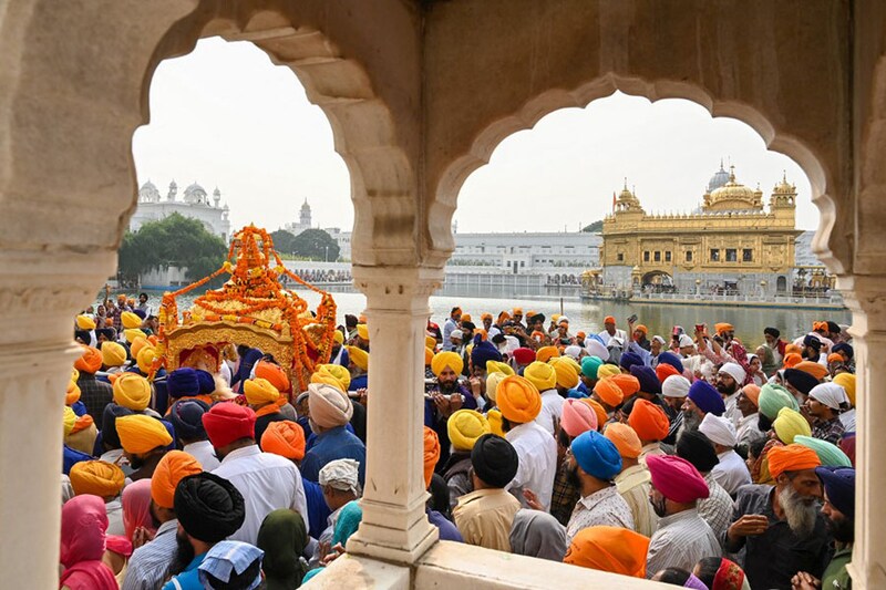 Sikh devotees carry the Guru Granth Sahib in a golden palanquin during a religious procession on the eve of the birth anniversary of Guru Nanak Dev, at the Golden Temple in Amritsar on November 7, 2022.