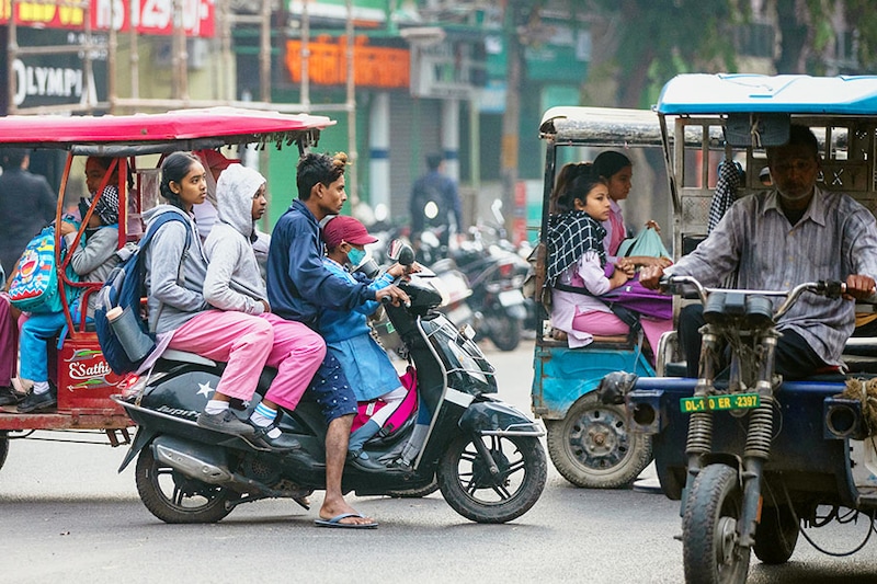A man ferries three school children on a bike in New Delhi, India on November 15, 2022. The world"s total population hits 8 billion today, according to UN estimates. After China, India is currently the world"s second most populous country, with about 1.4 billion people. After adding the most millions over a century, India and China will lead in global population decline by 2100.