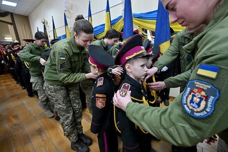 Ukrainian military students attach shoulder straps to a young cadet during the solemn initiation ceremony of the "Cadet Corps" lyceum-boarding school in Kyiv on November 18, 2022