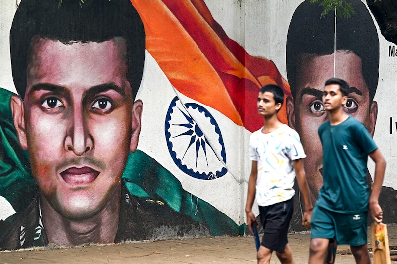 Youth walk past a mural of Major Sandeep Unnikrishnan, killed during the 2008 terror attack, on the 14th anniversary of the Mumbai militant attacks, in Mumbai on November 26, 2022.