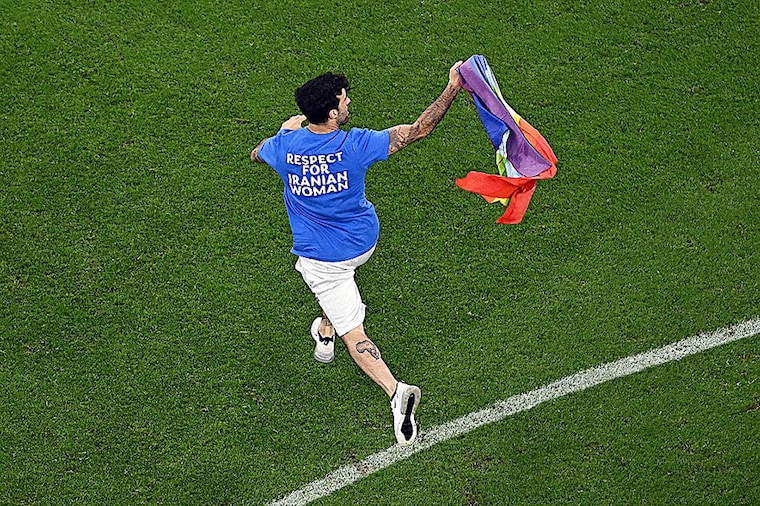 A spectator invades the pitch in a t-shirt that reads "Respect for Iranian woman" and waves an LGBT flag during the Qatar 2022 World Cup Group H football match between Portugal and Uruguay at the Lusail Stadium in Lusail, north of Doha on November 28, 2022.