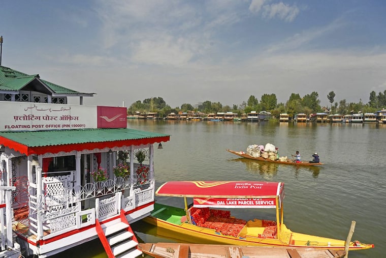 A man steers his boat past a floating post office at the Dal Lake in Srinagar on October 12, 2022.