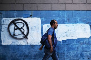 A man walks past a wall painted with an anti-bitcoin protest symbol, in San Salvador, on October 18, 2022. Most Salvadorans have not used bitcoin so far this year and consider that the emblematic bet of President Nayib Bukele has been a failure, assured Tuesday a poll of the private Central American University (UCA, Jesuit). Photo: Marvin RECINOS / AFP