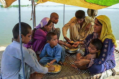 A flood-affected family eats a meal in a makeshift tent in Dera Allah Yar town of Jaffarabad district in Balochistan province, Pakistan on September 17, 2022. The catastrophic floods have hit 3.3 crore people, sweeping away homes, markets, crops and livestock, causing a massive outbreak of water-borne diseases and an estimated $30 billion in damages. The government now estimates that the cash-starved country will have negative growth this year.