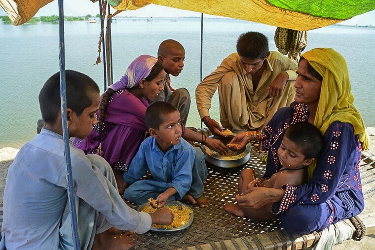 A flood-affected family eats a meal in a makeshift tent in Dera Allah Yar town of Jaffarabad district in Balochistan province, Pakistan on September 17, 2022. The catastrophic floods have hit 3.3 crore people, sweeping away homes, markets, crops and livestock, causing a massive outbreak of water-borne diseases and an estimated $30 billion in damages. The government now estimates that the cash-starved country will have negative growth this year.