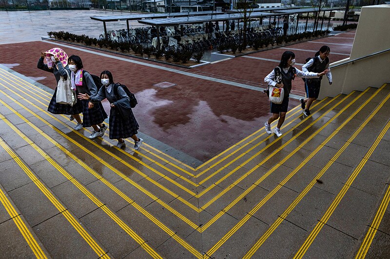 Junior high school students battling the rainy weather arrive on the first day of the new academic year at New Sannan Junior High School on April 07, 2023 in Tamba, Japan. The newly constructed school was opened today for the students of two recently closed junior high schools. More than 300 schools have closed across Japan annually in the past ten years due to dwindling birth rates and migration to urban areas.