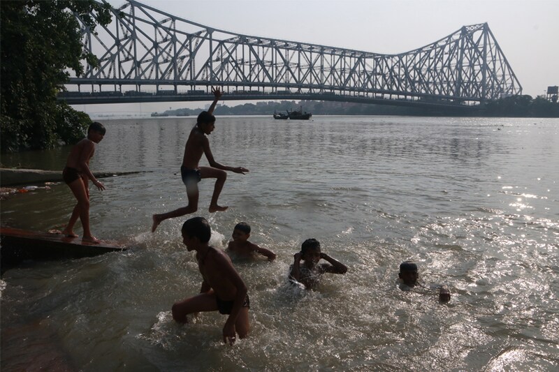 A boy leaps into the Ganga river at the Howrah Bridge on a hot day in Kolkata, India on April 10, 2023. IMD has forecast heatwave conditions in the coming days as temperatures rise in many parts of the country.
