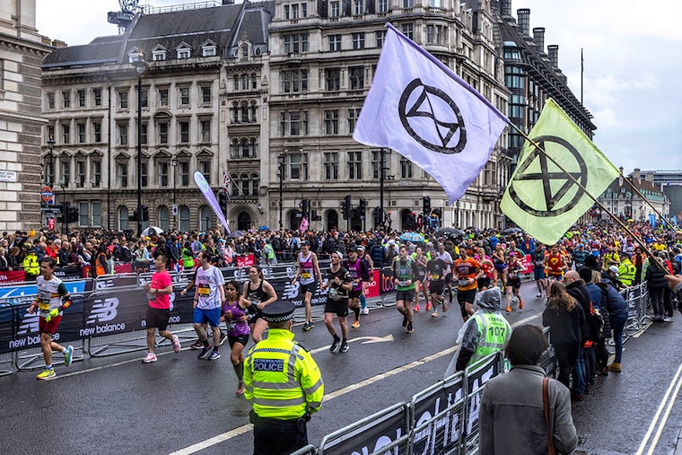 Extinction Rebellion protesters wave flags as London Marathon runners pass through Parliament Square on April 23, 2023, in London, England. XR and like-minded groups are inviting members of the public to the Unite to Survive event at "The Big One". This is a four-day action running from the 21st to the 24th of April where people will gather throughout Westminster and at the Houses of Parliament hoping to put pressure on politicians to act on climate change.