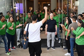 Chief Executive Officer of Apple Tim Cook (centre R) looks on next to Apple employees cheering as a customer enters Apple"s first retail store in India during its opening in Mumbai on April 18, 2023.
Image: Punit Paranjpe / AFP