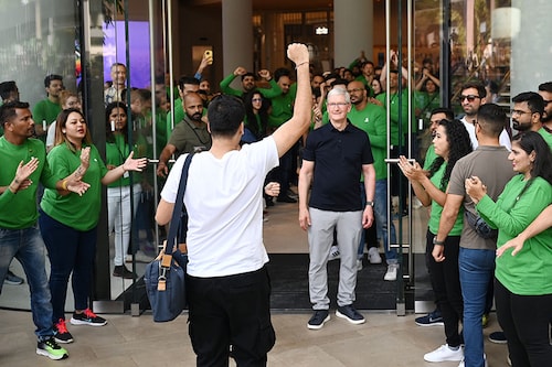 Chief Executive Officer of Apple Tim Cook (centre R) looks on next to Apple employees cheering as a customer enters Apple"s first retail store in India during its opening in Mumbai on April 18, 2023.
Image: Punit Paranjpe / AFP Chief Executive Officer of Apple Tim Cook (centre R) looks on next to Apple employees cheering as a customer enters Apple"s first retail store in India during its opening in Mumbai on April 18, 2023.
Image: Punit Paranjpe / AFP