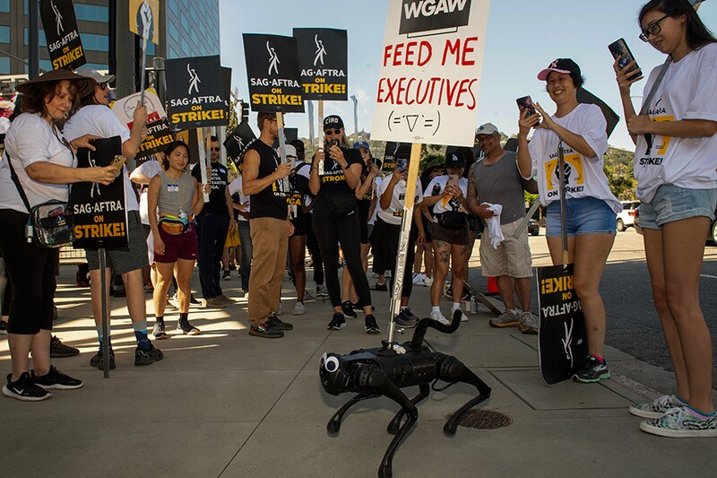 Robot dog G4t0 walks among members of the Writers Guild of America and the Screen Actors Guild as they walk the picket line outside of Universal Studios in Burbank, California, on August 4, 2023. - Tens of thousands of Hollywood actors went on strike at midnight July 13, 2023, effectively bringing the giant movie and television business to a halt as they join writers in the first industry-wide walkout for 63 years.