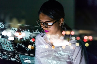 A woman wearing glasses looks at code on a computer screen.
Image: Shutterstock