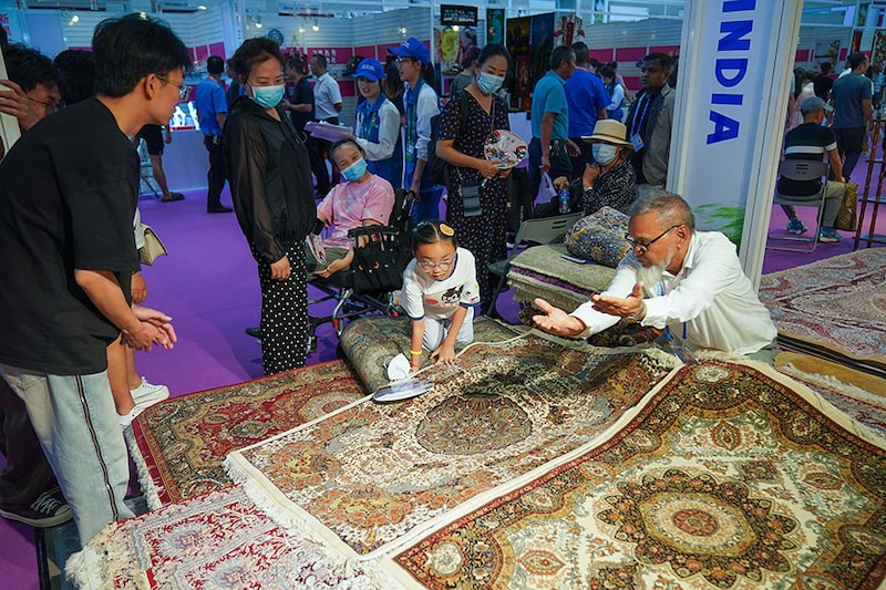 A chinese girl looks at carpets from India during the 7th China-South Asia Exposition at Kunming Dianchi Exhibition Centre in Kunming, Yunnan Province of China, on August 16, 2023. Themed on "Solidarity and Coordination for Common Development", the five-day event - with 15 exhibition halls including a biomedicine and healthcare pavilion - has evolved into a vital platform fostering economic and trade cooperation between China, South Asia and Southeast Asian countries.