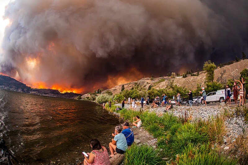 Residents watch the McDougall Creek wildfire in West Kelowna, British Columbia, Canada, on August 18, 2023, from Kelowna. Evacuation orders were put in place for areas near Kelowna, as the fire threatened the city of around 150,000. Canada is experiencing a record-setting wildfire season, with official estimates of over 13.7 million hectares (33.9 million acres) already scorched. Four people have died so far.