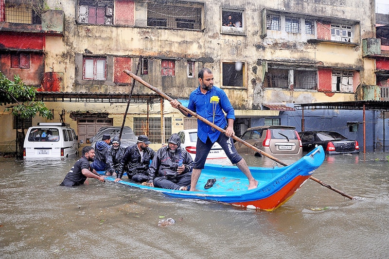 People move in a boat past partially submerged vehicles in a residential area following heavy rains ahead of Cyclone Michaung in Chennai, India, December 4, 2023.