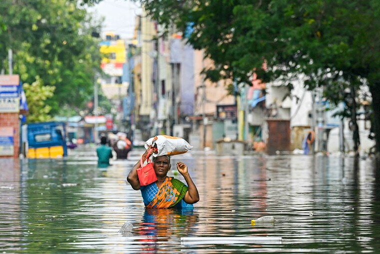 Along with her belongings, a woman wades through a flooded street after heavy rains in Chennai on December 6, 2023. Chest-high water surged down the streets of India"s southern city, Chennai, on December 5, with eight people killed in intense floods as Cyclone Michaung made landfall on the southeast coast.