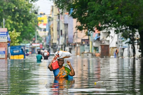 Along with her belongings, a woman wades through a flooded street after heavy rains in Chennai on December 6, 2023. Chest-high water surged down the streets of India"s southern city, Chennai, on December 5, with eight people killed in intense floods as Cyclone Michaung made landfall on the southeast coast.