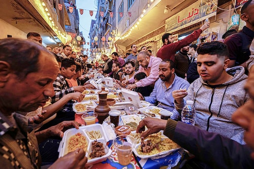 Egyptian Muslims gather in streets lined with long tables to break their Ramadan fast together in a mass "iftar" meal in Ezbet Hamada in Cairo"s Matariya suburb. Image: Khaled Desouki / AFP