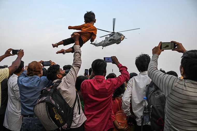 People watch and record on their cellphones a helicopter flying near Gateway of India on the occasion of the Navy week celebration in Mumbai. Beating Retreat and Tattoo Ceremony (BRTC) is held as a part of the Navy week celebration near Gateway of India.