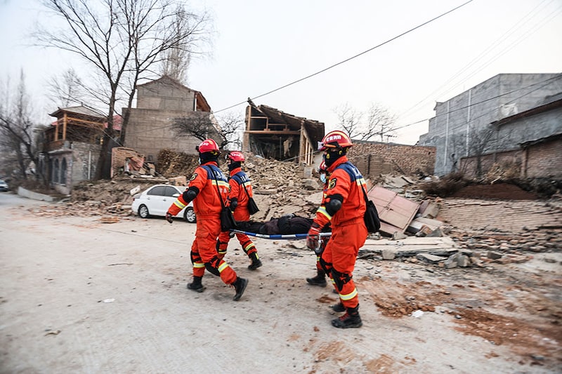 Rescue workers carry a victim after an earthquake in Dahejia, Jishishan County, in northwest Chinaàs Gansu province on December 19, 2023. At least 111 people were killed when an earthquake collapsed buildings in northwest China, state media reported on December 19. Rescue workers raced to start digging through rubble.