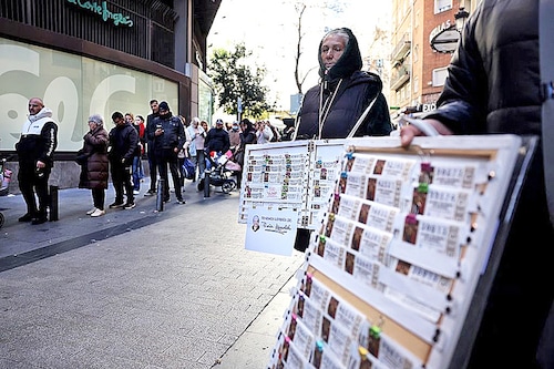 Street vendors stand as people queue to buy Christmas lottery tickets outside the popular lottery outlet "Dona Manolita" on December 18, 2023 in central Madrid. Image: THOMAS COEX / AFP