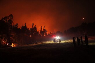 Firefighters are seen during a fire in Puren, Araucania region, Chile, February 5, 2023. Chile has extended an emergency declaration to several central-southern regions after a devastating heat wave provoked forest fires that left at least 23 people dead and over 979 injured. Official data released late Friday showed that some 40,000 hectares (99,000 acres) have been burned by the fires due to climate change"s evolution.