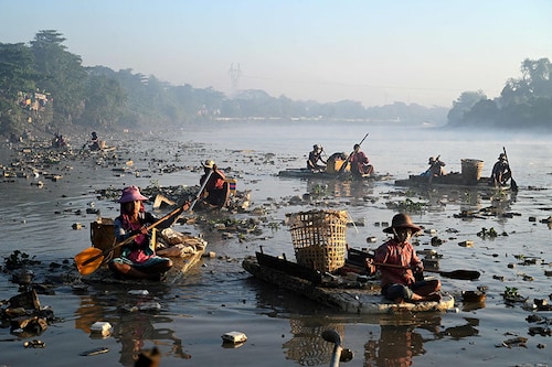 Waste collectors paddling polystyrene boats as they look for plastic and glass to recycle in Pazundaung Creek in Yangon. Image: Sai Aung Main / AFPÂ©