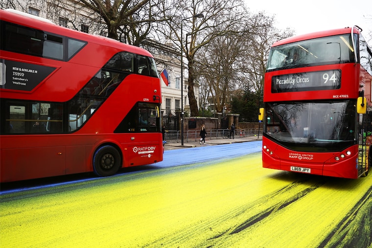 Buses drive on paint in the colours of the Ukrainian flag, after Protest group "Led by Donkeys" spread paint on the road, ahead of the first anniversary of Russia"s invasion of Ukraine, outside the Russian Embassy in London, Britain February 23, 2023.