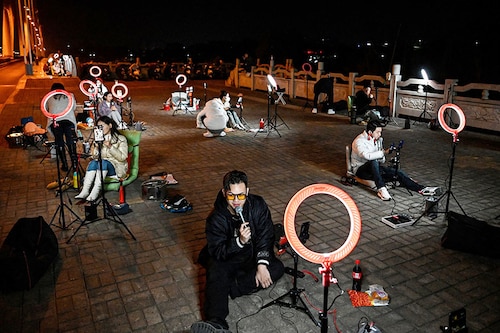 Outdoor livestreamers singing and chatting with the audiences through their mobile phones on an overpass bridge at night in Guilin
Image: Jade Gao / AFPÂ©