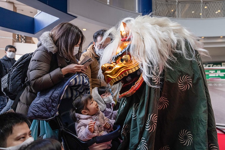 YOKOHAMA, JAPAN - 2/01/2023: Shishi-mai lion dancer performs his dance to celebrate the new year and to bring good luck and fortune to visitors of a shopping mall in Yokohama. The Shishi-Mai Lion Dance is a celebratory dance to welcome the new year and brings good luck and fortune to the people according to many Asian cultures. Parents let the lion symbolically bite their children to scare away evil spirits.