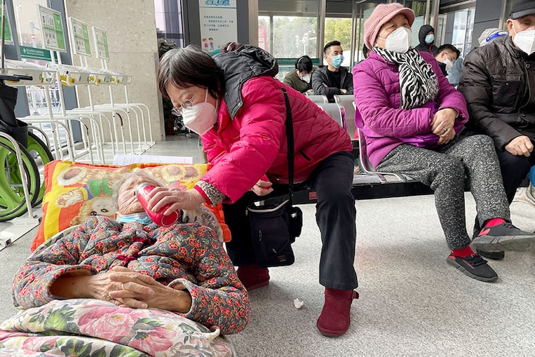 A woman gives a drink to an elderly person lying on a stretcher while waiting in the emergency department of a hospital, amid the coronavirus disease (COVID-19) outbreak in Shanghai, China, January 5, 2023.